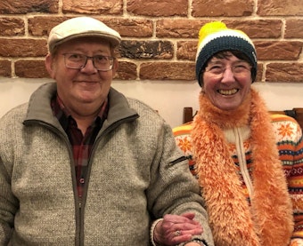 Älteres lachendes Paar mit Mützen im Café.