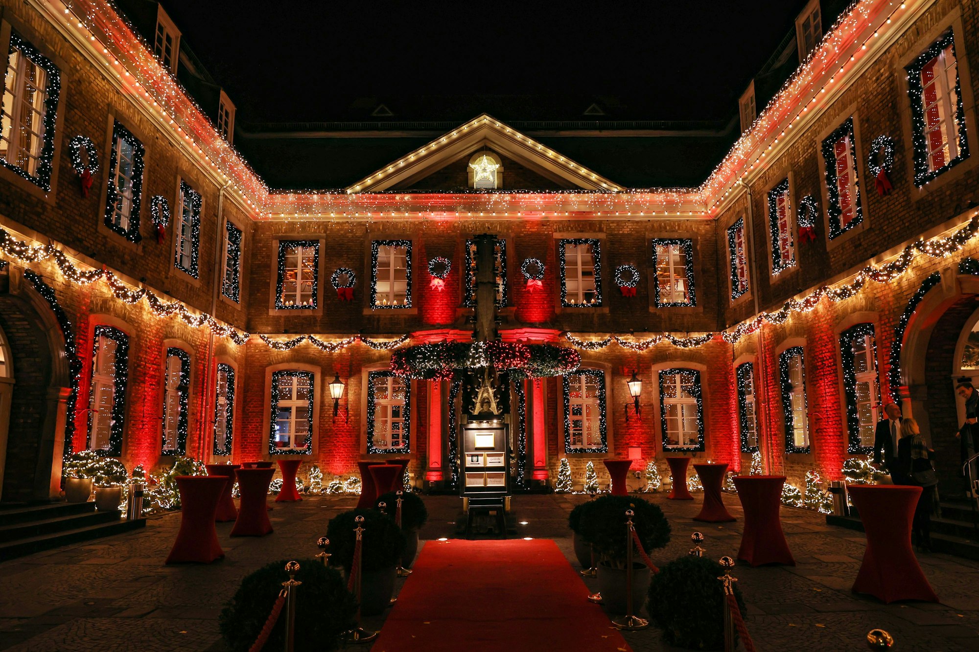 Der Innenhof der Wolkenburg ist mit zahlreichen Lichterketten sowie roten Scheinwerfern beleuchtet. An allen Fenstern hängen Girlanden.