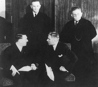 Reichskanzler Adolf Hitler spricht mit dem Vizekanzler Franz von Papen; dahinter stehen die Minister Werner von Blomberg (Militär) und Alfred Hugenberg (Wirtschaft). Sie gehören zum ersten Kabinett Hitler 1933.