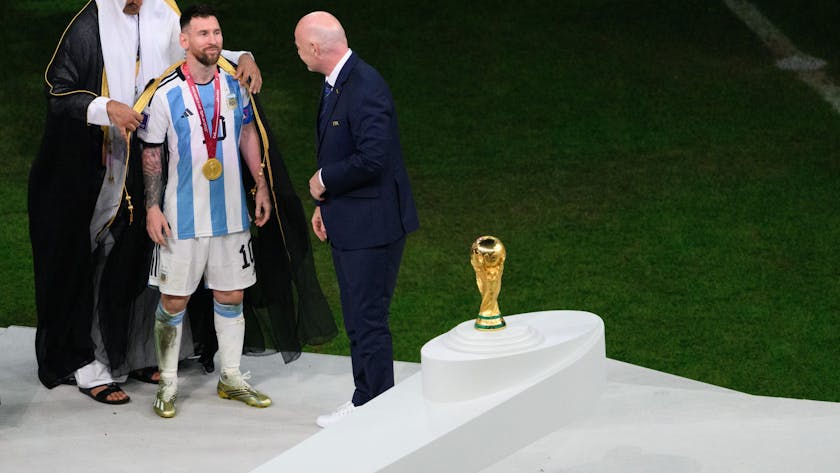 Der Emir von Katar, Scheich Tamim bin Hamad Al Thani (l), legt Argentiniens Lionel Messi vor Übergabe des WM-Pokals vor Fifa-Präsident Gianni Infantino ein Bischt, ein traditionelles arabische Kleidungsstück an.