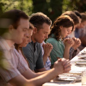 Eine Großfamilie betet am Essenstisch.