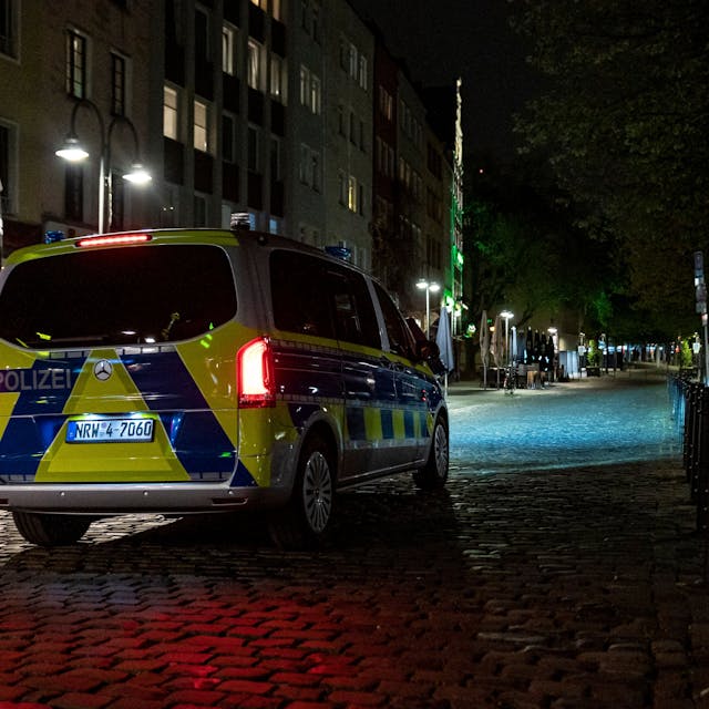 Ein Polizeibus steht auf einer Straße mit Kopfsteinpflaster bei Nacht.
