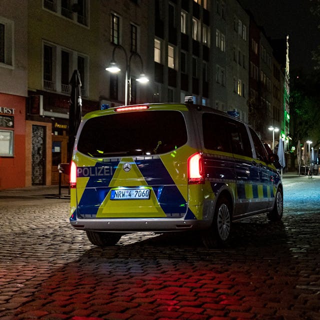 Ein Polizeibus steht auf einer Straße mit Kopfsteinpflaster bei Nacht.