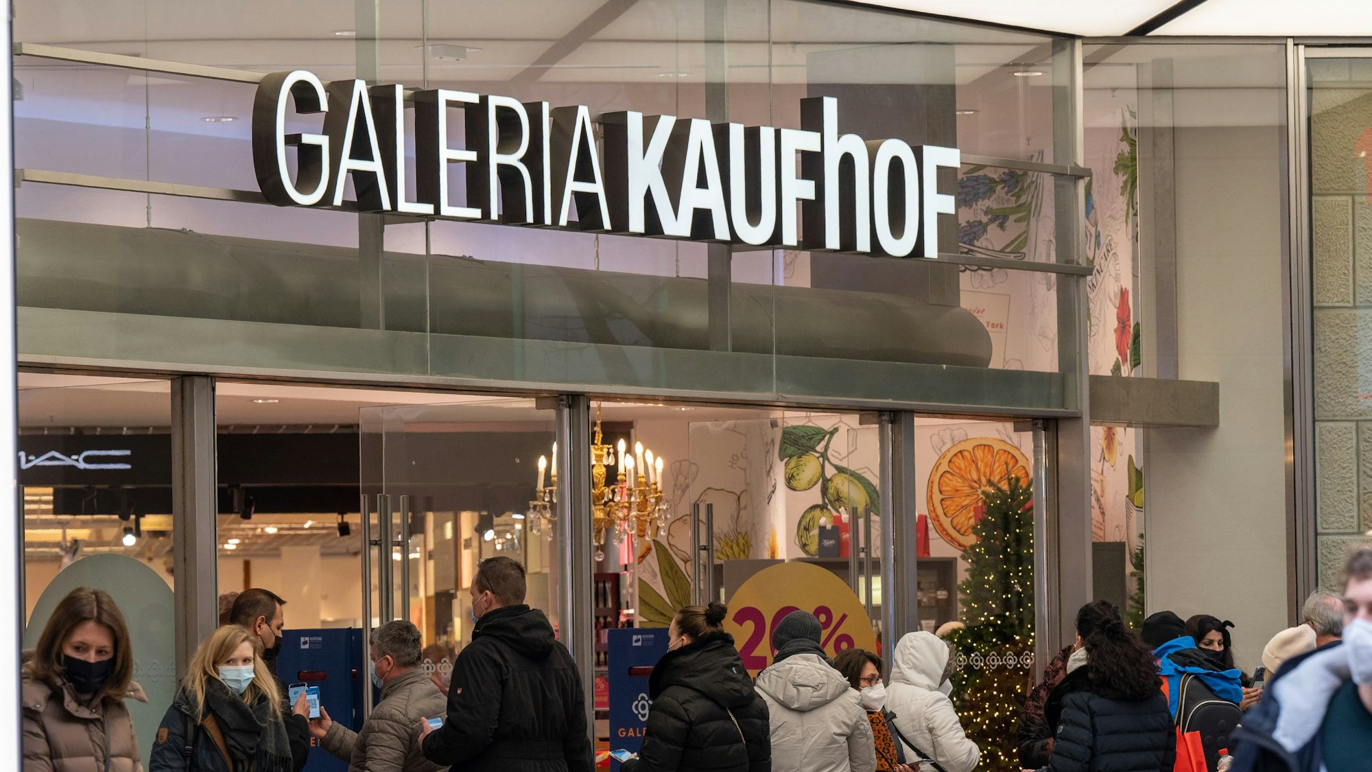 Menschen stehen in einer Schlange vor dem Eingang von Galeria Kaufhof in Köln.