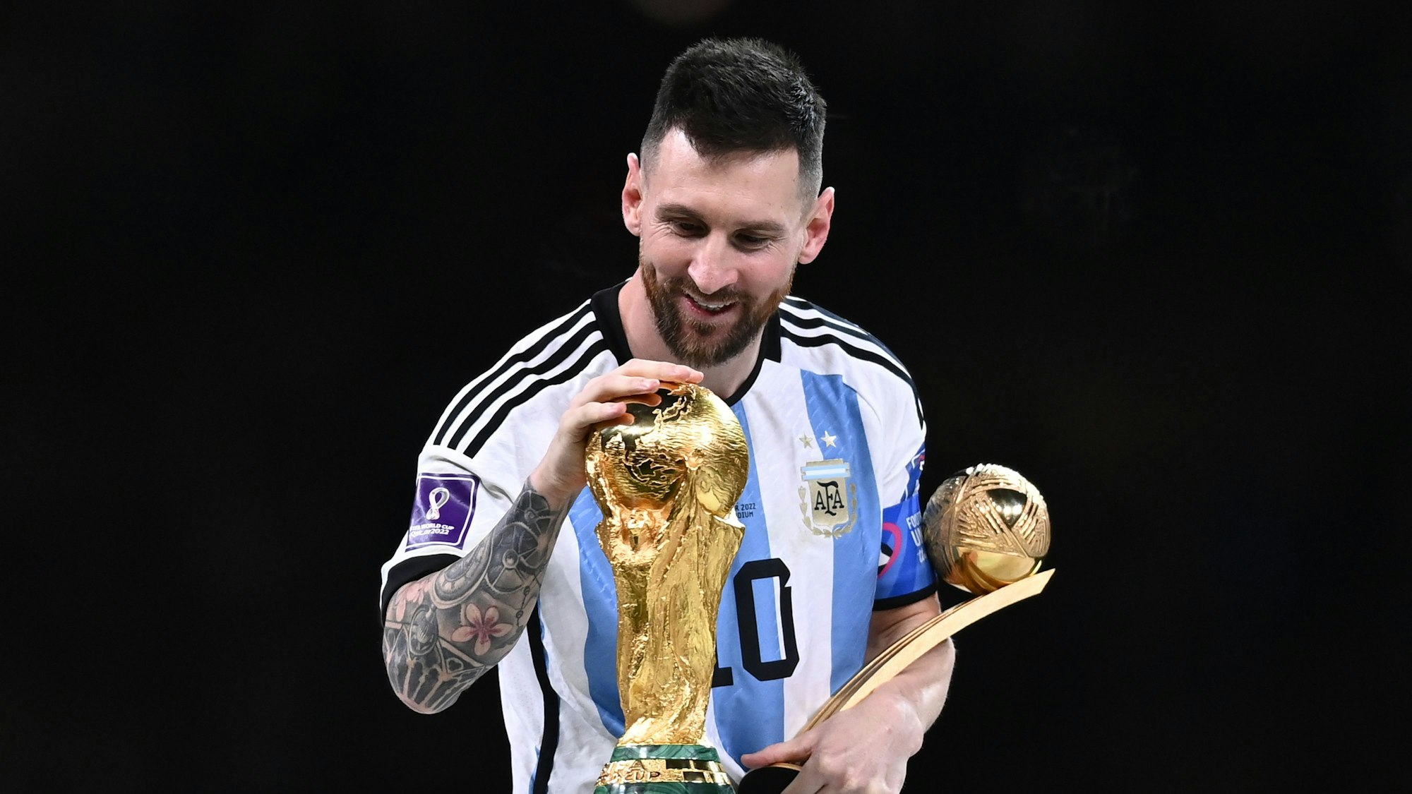 Lionel Messi berührt den Weltmeisterpokal.
