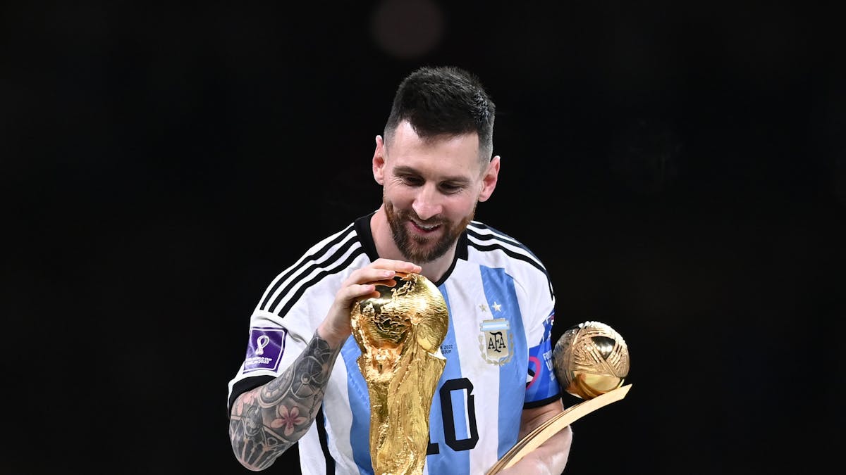 Lionel Messi berührt den Weltmeisterpokal.