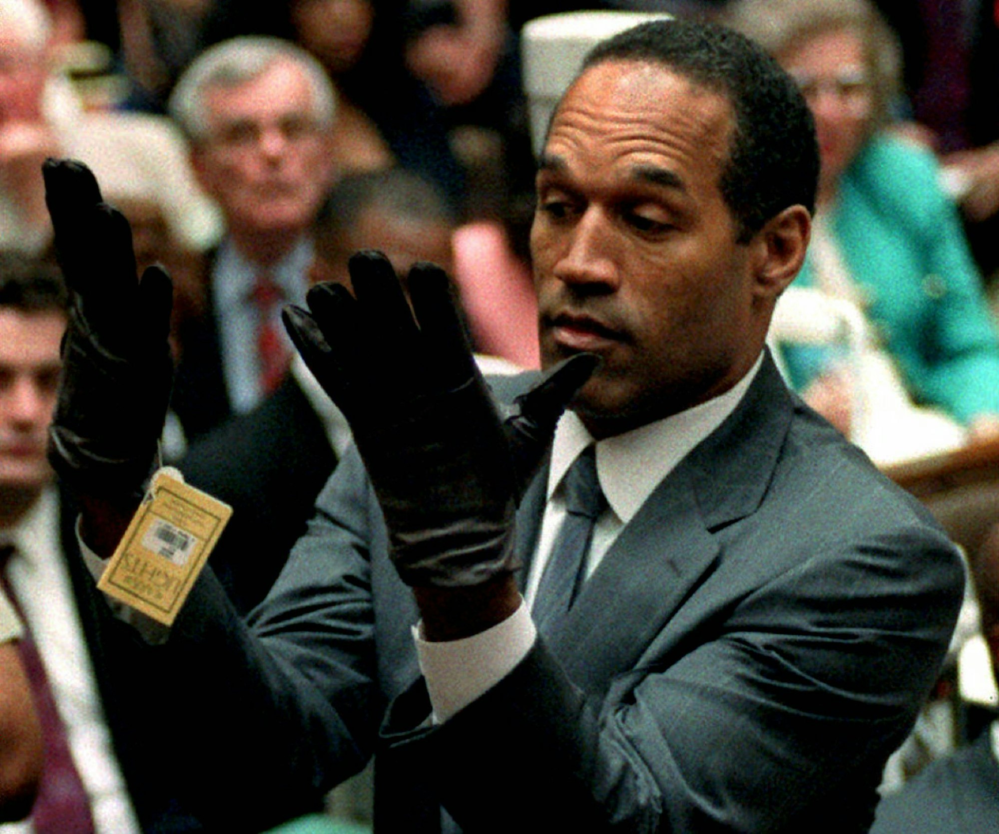 O.J. Simpson betrachtet in seinem Prozess 1995 ein neues Paar Aris-Handschuhe, die er während seines Doppelmordprozesses auf Geheiß der Staatsanwaltschaft vor den Geschworenen anziehen musste