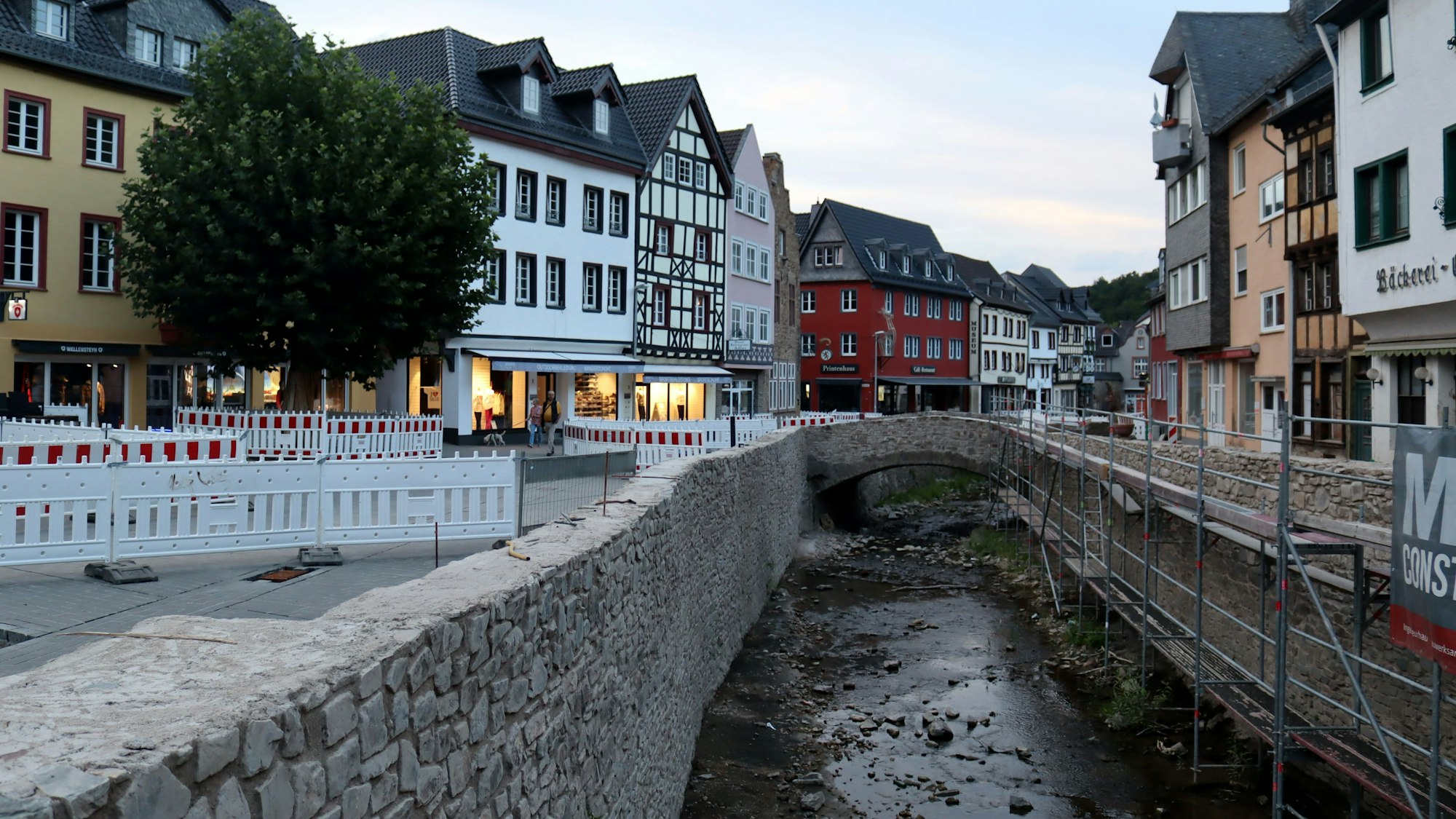Die Stadt Bad Münstereifel bei einer Aufnahme in den Abendstunden im August 2022. Die Erft ist noch voller Steine, die Mauern noch nicht komplett wiederhergestellt, der Markt ist abgesperrt wegen Wiederaufbauarbeiten.