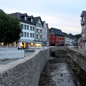 Die Stadt Bad Münstereifel bei einer Aufnahme in den Abendstunden im August 2022. Die Erft ist noch voller Steine, die Mauern noch nicht komplett wiederhergestellt, der Markt ist abgesperrt wegen Wiederaufbauarbeiten.