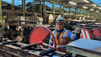 Ein Mann in Warnweste und mit Sicherheitshelm steht an einer Maschine der Brikettfabrik am Wachtberg.