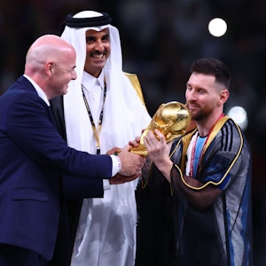 Argentiniens Lionel Messi (r) nimmt den Weltmeisterpokal vom Emir von Katar, Scheich Tamim bin Hamad Al Thani (M) und FIFA-Präsident Gianni Infantino entgegen.