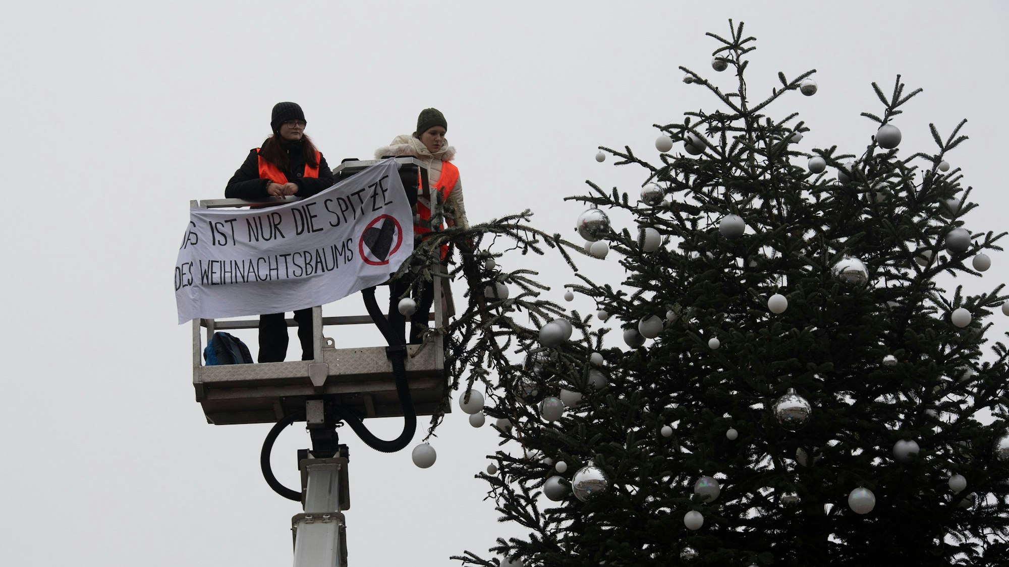 Ohne Spitze steht der Weihnachtsbaum vor dem Brandenburger Tor. Zwei Aktivisten der Umweltschutzgruppe Letzte Generation fuhren mit einem Hubwagen vor dem Tannenbaum auf dem Pariser Platz am Brandenburger Tor.