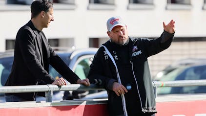 FC-Geschäftsführer Christian Keller und Trainer Steffen Baumgart unterhalten sich am Rande des Trainings des 1. FC Köln am Geißbockheim. Baumgart lehnt an der Bande und gestikuliert, Keller steht dahinter.&nbsp;