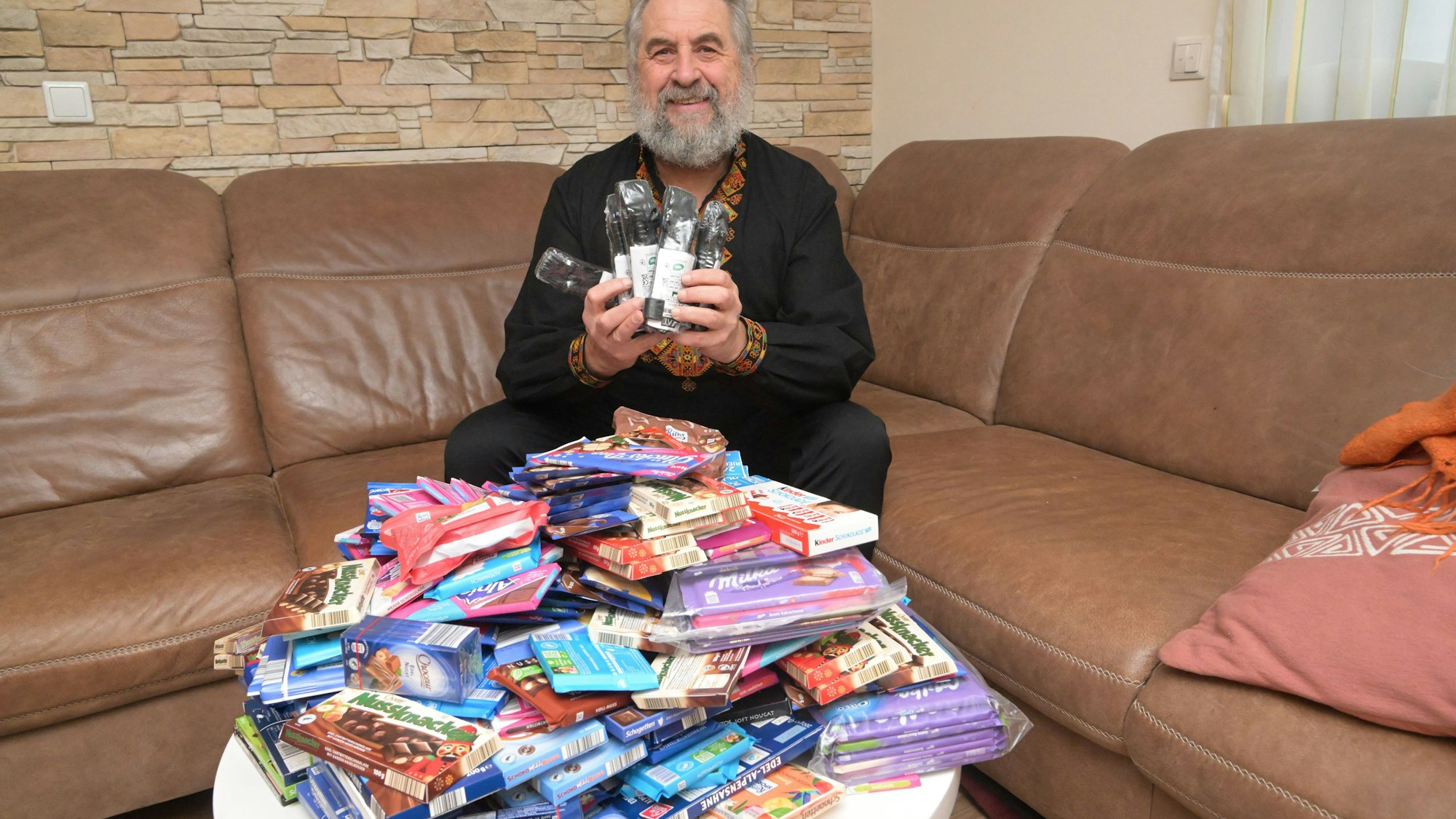 Paul sitzt auf dem Wohnzimmersofa und zeigt medizinische Armbinden und Süßigkeiten, die er mit in die Ukraine nimmt.
