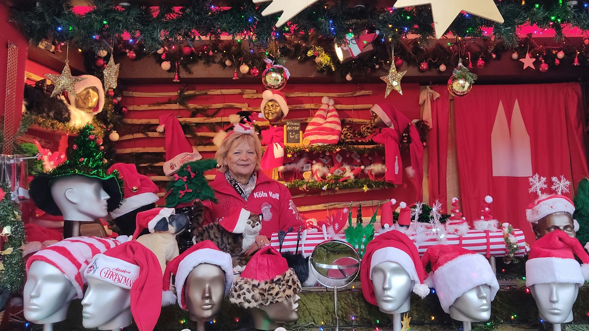 Marlene Esser steht in ihrem Weihnachtsmarktstand am Kölner Dom. Dort verkauft sie Weihnachtsmann-Mützen mit Logo des 1. FC Köln und andere Weihnachtsartikel mit Köln-Bezug.