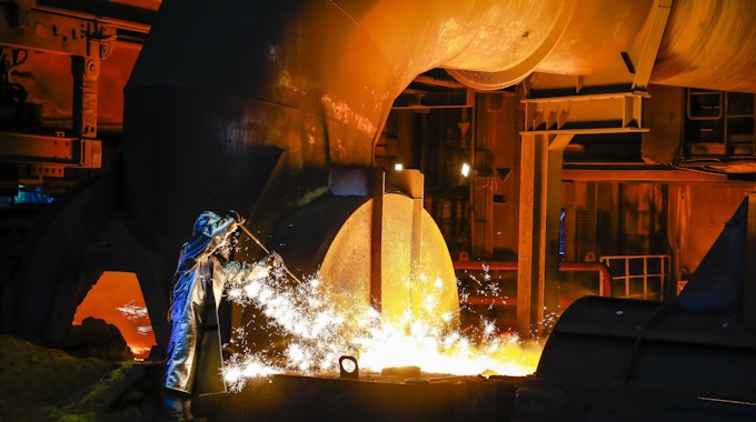 ThyssenKrupp Steel, ein Stahlarbeiter im Schutzanzug entnimmt eine 1500 Grad heisse Roheisenprobe.