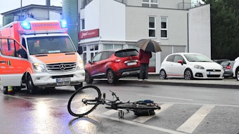 Ein Fahrrad liegt auf der Straße. Ein Rettungswagen steht dahinter, das Blaulicht ist eingeschaltet.