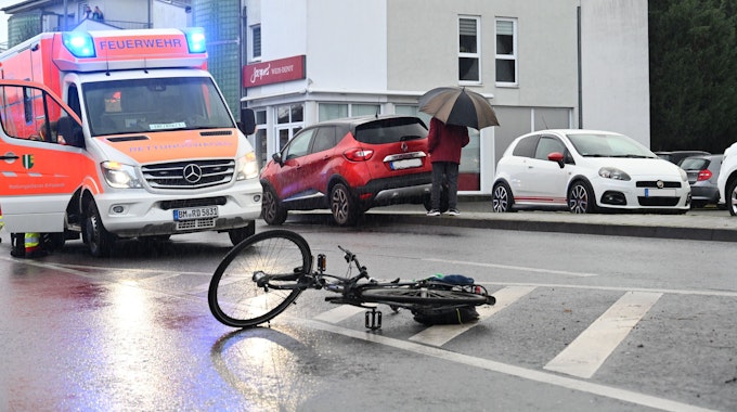 Ein Fahrrad liegt auf der Straße. Ein Rettungswagen steht dahinter, das Blaulicht ist eingeschaltet.