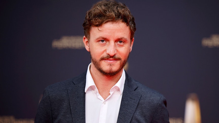 Tommi Schmitt, hier bei der Verleihung des Deutschen Fernsehpreises am 14. September 2022, lächelnd mit Anzug und weißem Hemd.