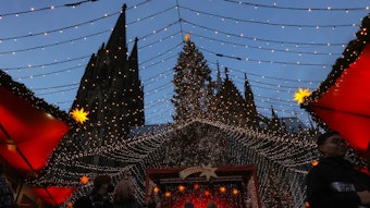 Die Spitzen des Kölner Dom erheben sich hinter dem Weihnachtsmarkt auf dem Roncalliplatz.



