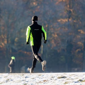 Ein Mann joggt durch den winterlichen Stadtpark.&nbsp;