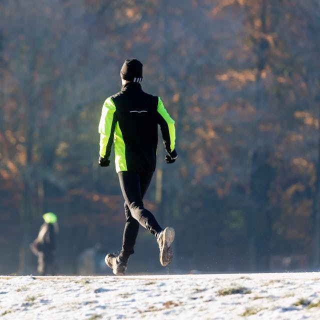 Ein Mann joggt durch den winterlichen Stadtpark.&nbsp;