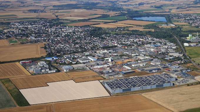 Drohnenansicht des Gewerbegebiets der Stadt Zülpich mit vielen Fabrikhallen und Feldern.