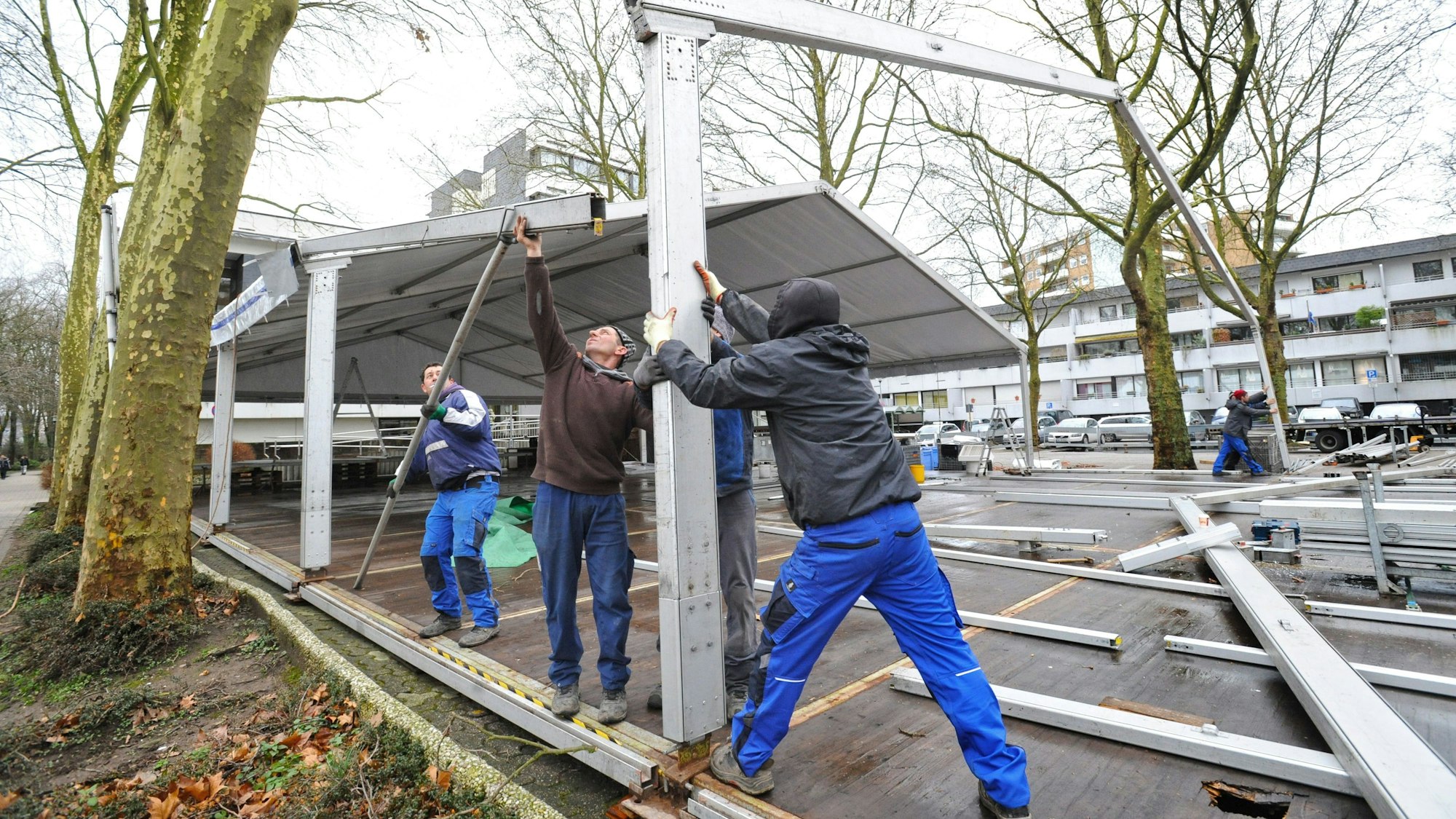 Drei Arbeiter bauen Gerüst und Dach des Karnevalszelts vor dem Leichlinger Rathaus auf.