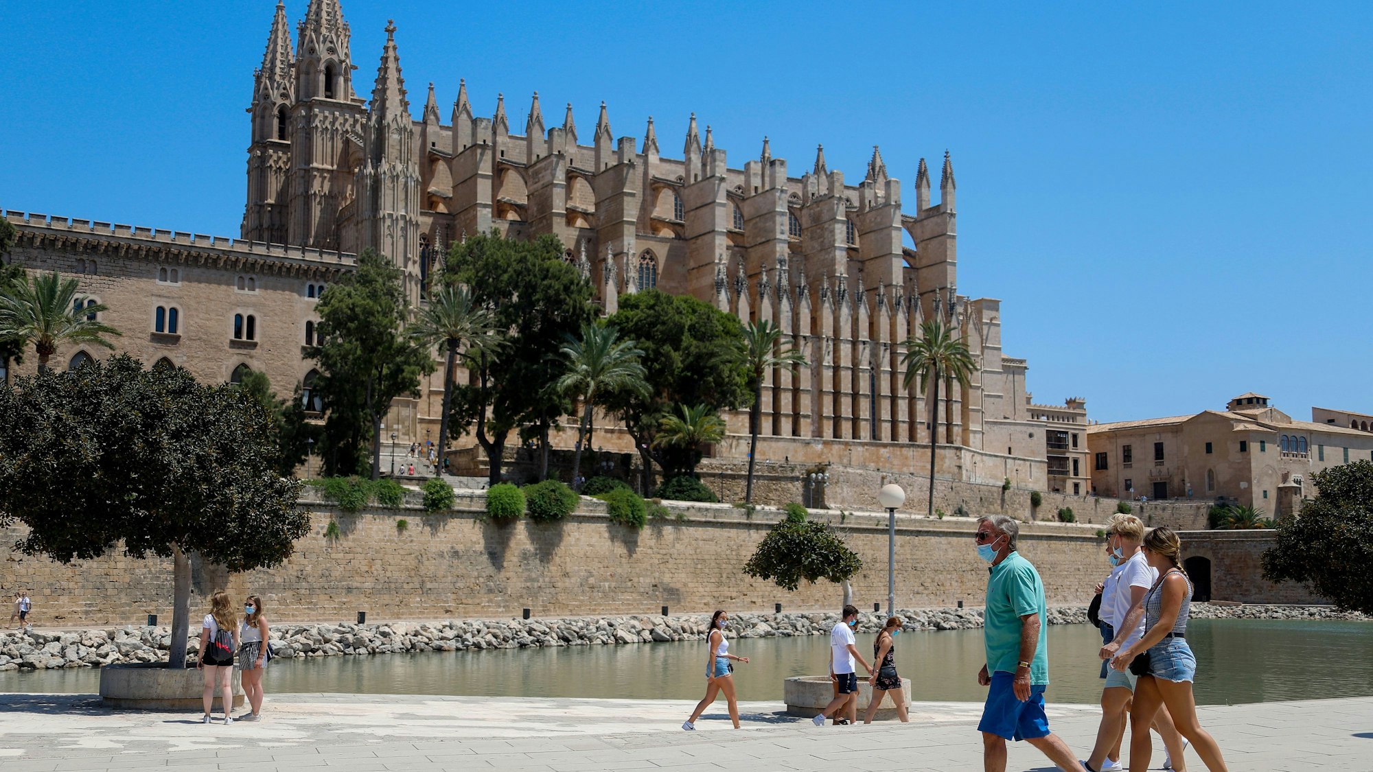 Touristen und Touristinnen gehen vor der Kathedrale von Palma auf Mallorca entlang. Die Aufnahme dient als Symbolfoto.