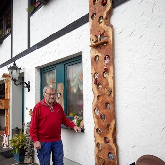Ein Mann steht an einem Adventskalender aus Holz.