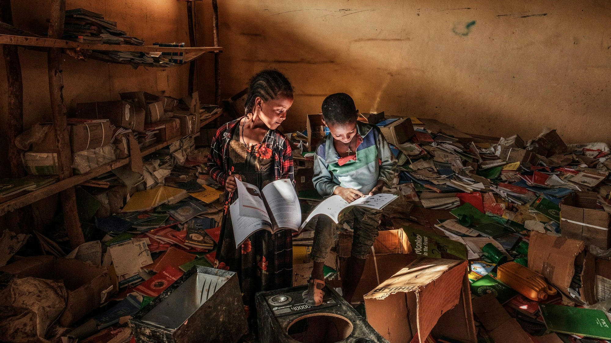 Kinder betrachten in einer äthiopischen Bibliothek Bücher, während außerhalb des Dorfs Kämpfe stattfinden.