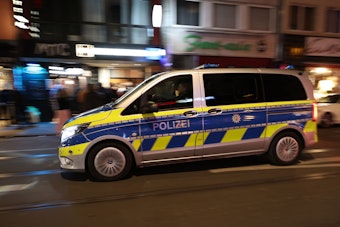 Ein Polizeiauto fährt bei Nacht über die Zülpicher Straße.