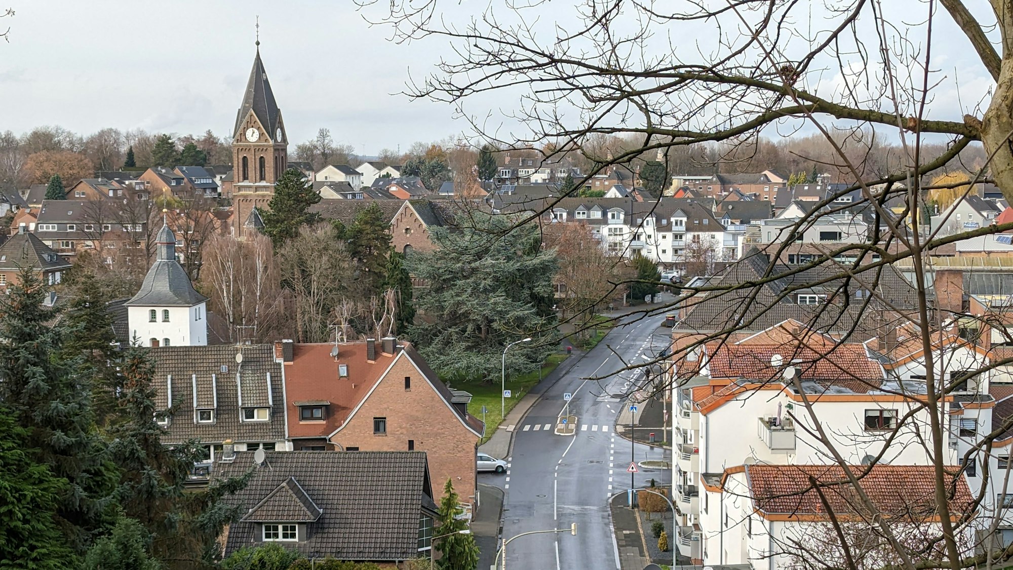 Ansicht von Alt-Hürth mit Straße und Kirche, bewölkt.