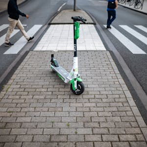 Ein E-Scooter des Unternehmens Lime steht vor einem Zebrastreifen in der Kölner Innenstadt.