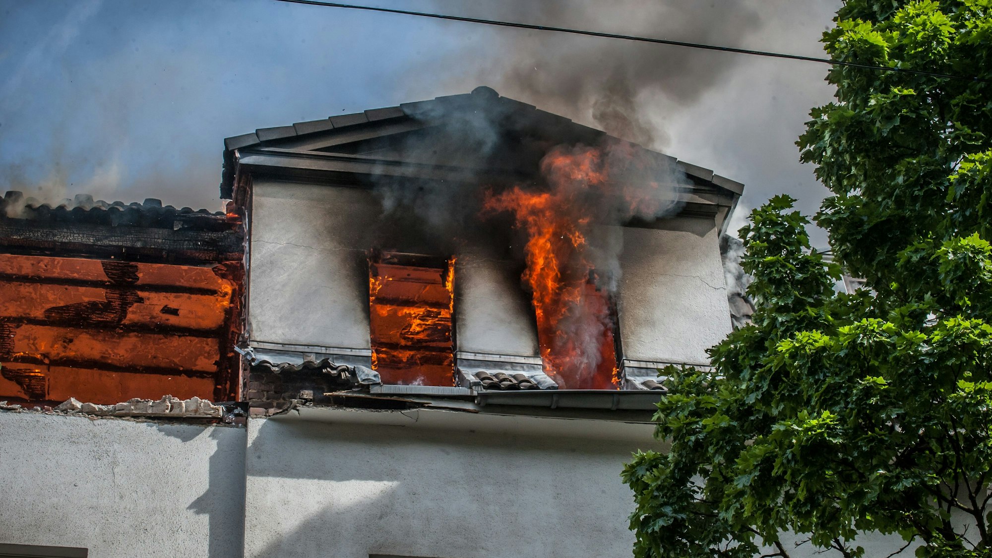 Aus dem Dachgeschoss eines Hauses in Opladen schlagen Flammen.