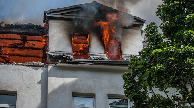 Aus dem Dachgeschoss eines Hauses in Opladen schlagen Flammen.