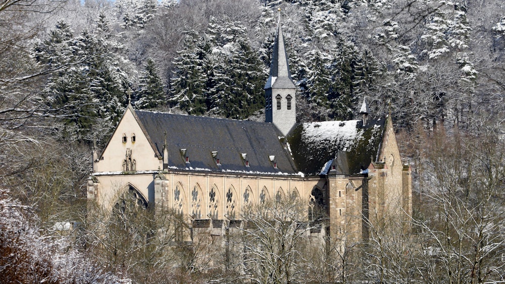 Der Altenberger Dom im Schnee, umgeben von schneeverzuckerten Bäumen.