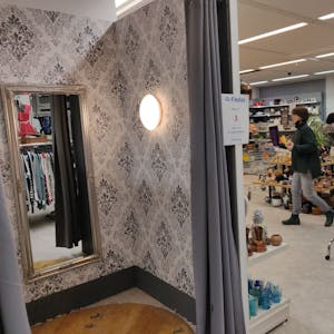 Blick in die tapezierte leere Umkleidekabine mit Spiegel im Sozialkaufhaus in Leichlingen.