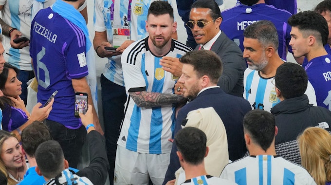 Ein Mann macht mit seinem Handy ein Foto von Nusret Gokce (Mitte rechts), auch bekannt als Koch oder Salt Bae, mit dem argentinischen Nationalspieler Lionel Messi am Ende des WM-Endspiels