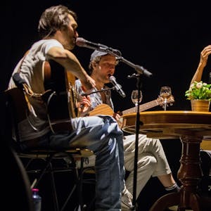 Christopher Annen, Severin Kantereit und Henning May sitzen auf der Bühne in der Lanxess-Arena an einem Tisch und machen Musik.