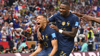 Kylian Mbappe jubelt nach seinem Treffer zum 2:2 für Frankreich im WM-Finale gegen Argentinien am 18. Dezember 2022 und schreit seine Freude heraus. Von hinten umarmt ihn Teamkollege Marcus Thuram.
