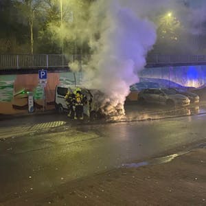 Ein brennendes Auto in Wipperfürth, Feuerwehrleute löschen das Fahrzeug.