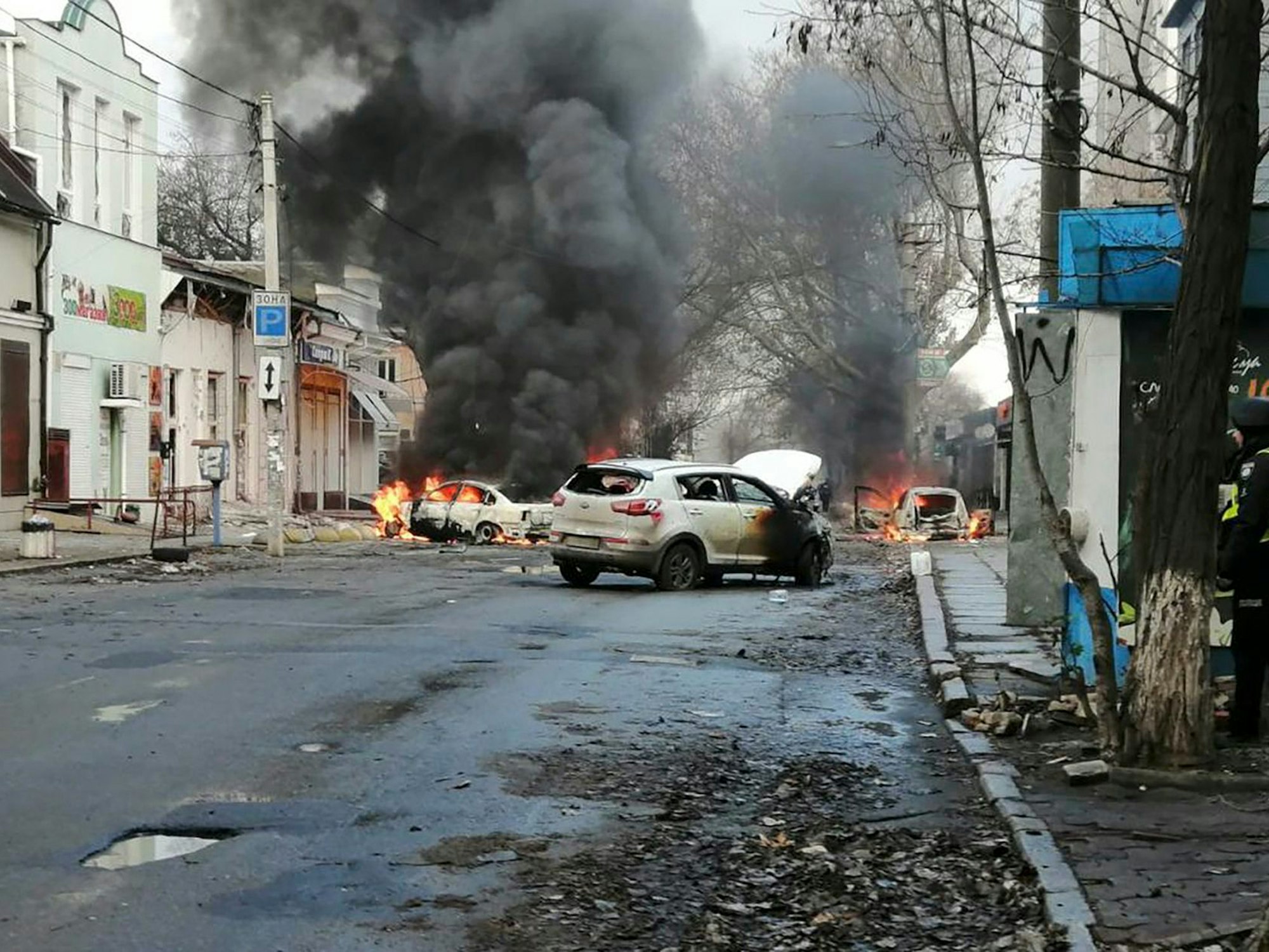 In Cherson (Ukraine) brennen am 24. Dezember 2022 Autos und Rauch steigt auf, nachdem ein russischer Raketenangriff das Stadtzentrum getroffen hat.