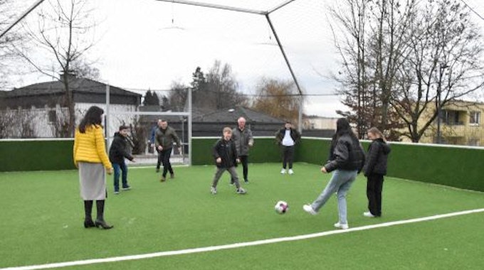 Auf einem Kunstrasenplatz spielen Jugendliche und Erwachsene Fußball.
