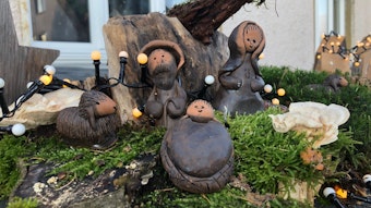 Krippenfiguren aus Ton liegen in einem Garten.