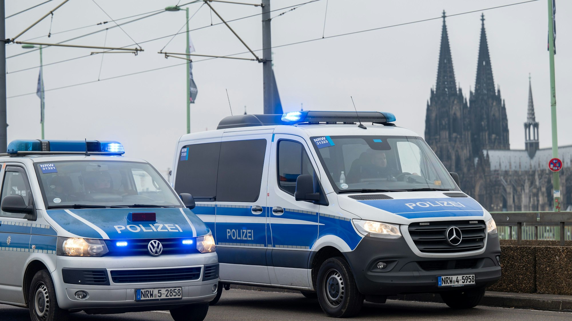 Zu sehen sind zwei Mannschaftswagen der Polizei Köln auf der Deutzer Brücke. Im Hintergrund zu sehen ist der Kölner Dom.