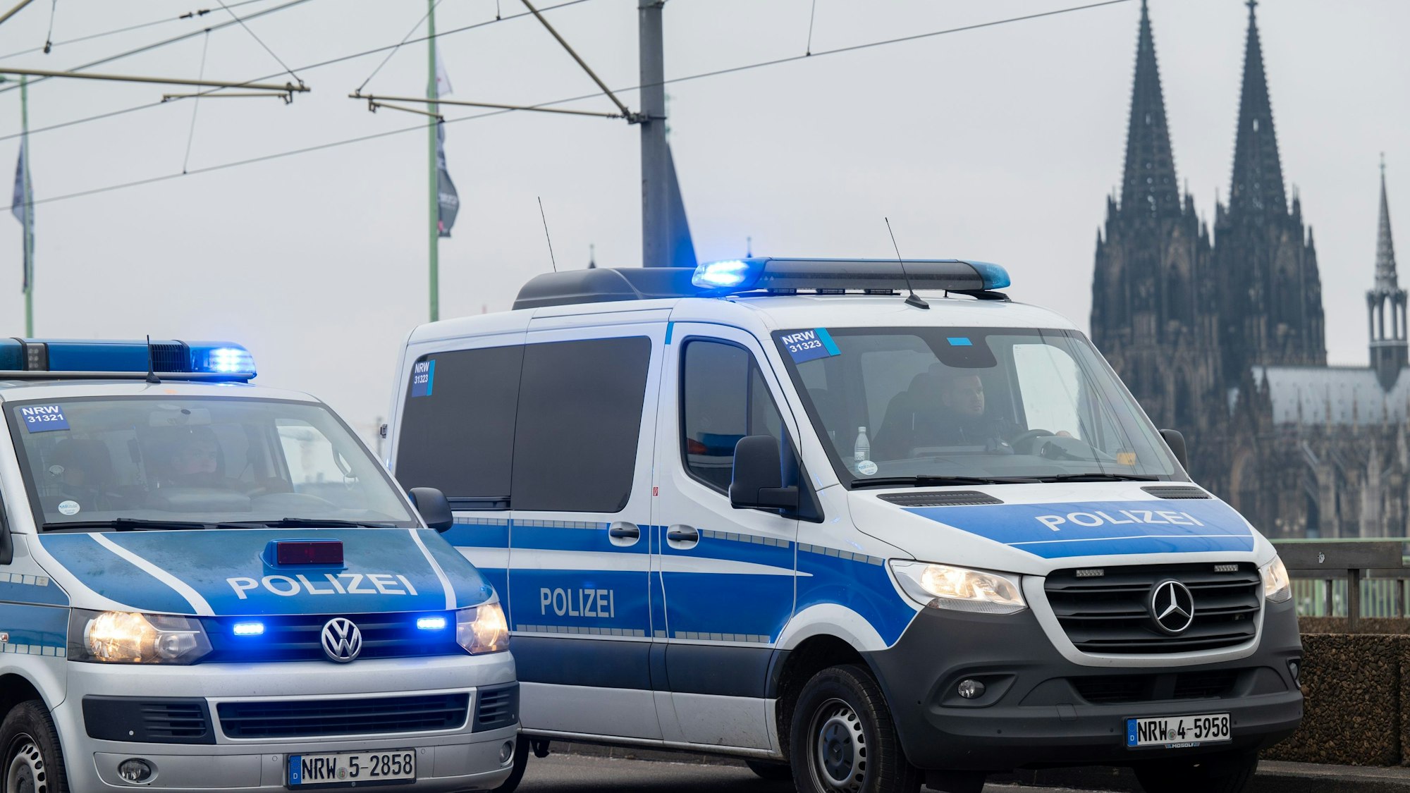 Zu sehen sind zwei Fahrzeuge der Polizei auf der Deutzer Brücke in Köln. Im Hintergrund ist der Kölner Dom zu sehen.