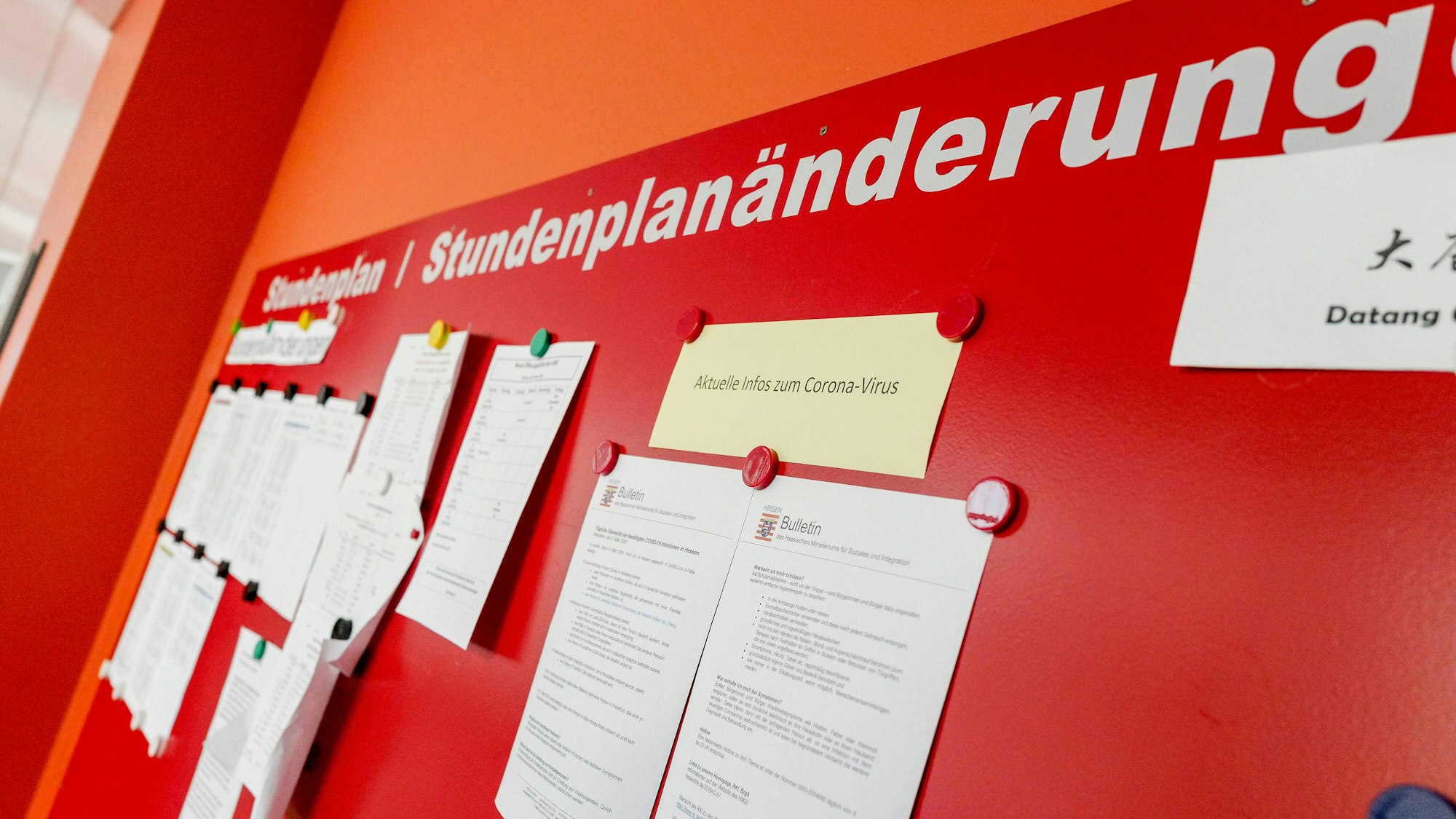 Auf einer roten Tafel mit der Überschrift „Stundenplan - Stundenplanänderung“ hängen zahlreiche Mitteilungen im DIN-A4-Format.