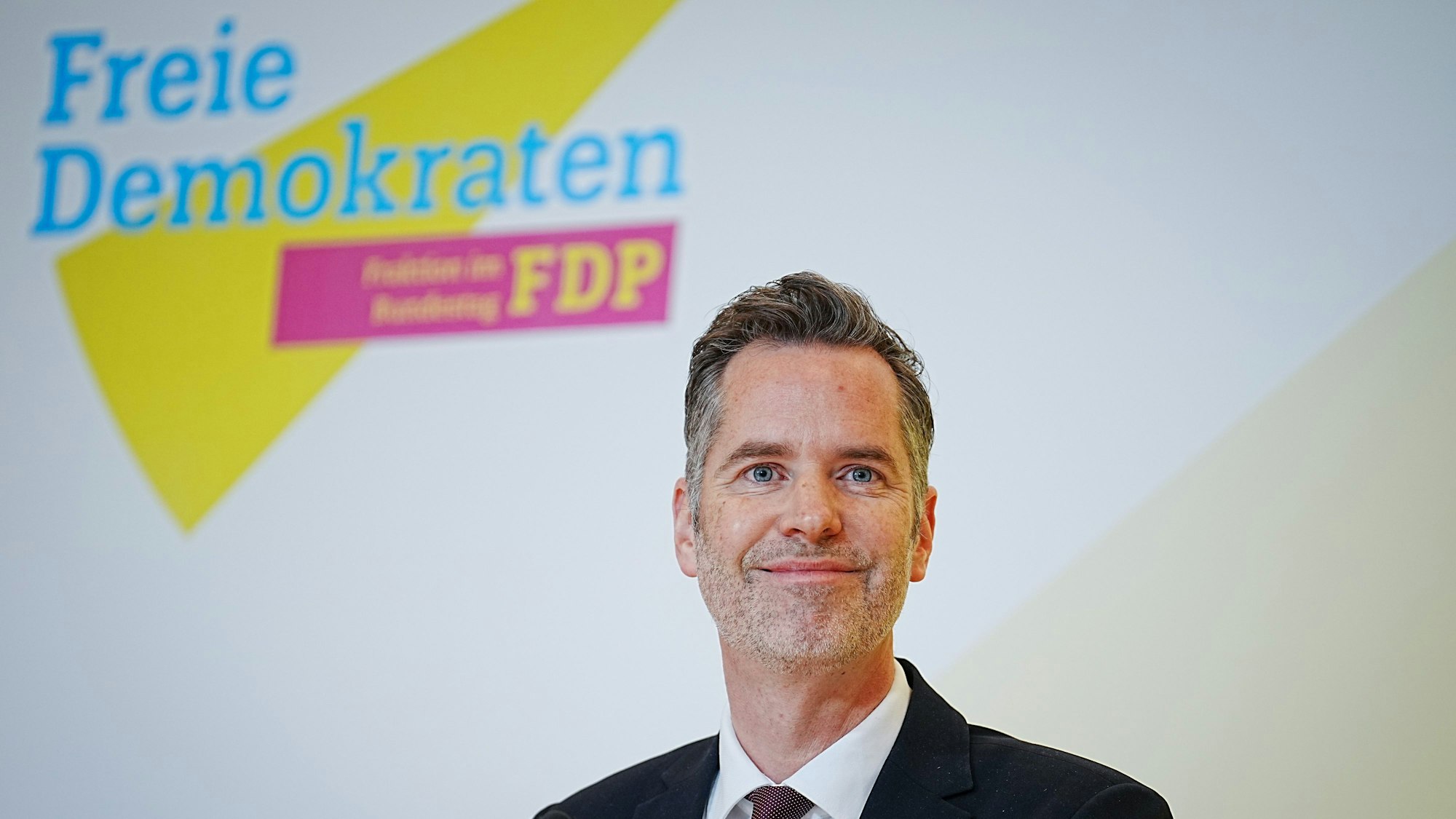 Es ist Christian Dürr zu sehen. Im Hintergrund sieht man das Logo der FDP.