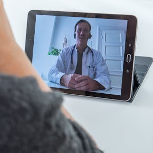 Ein Arzt, hier im Februar 2021 in Hamburg, ist per Videosprechstunde auf einem Tablet zu sehen. Die erste Video-Sprechstunde von Kinderärztinnen und Kinderärzten im Oberbergischen Kreis war laut Kassenärztlicher Vereinigung ein Erfolg.